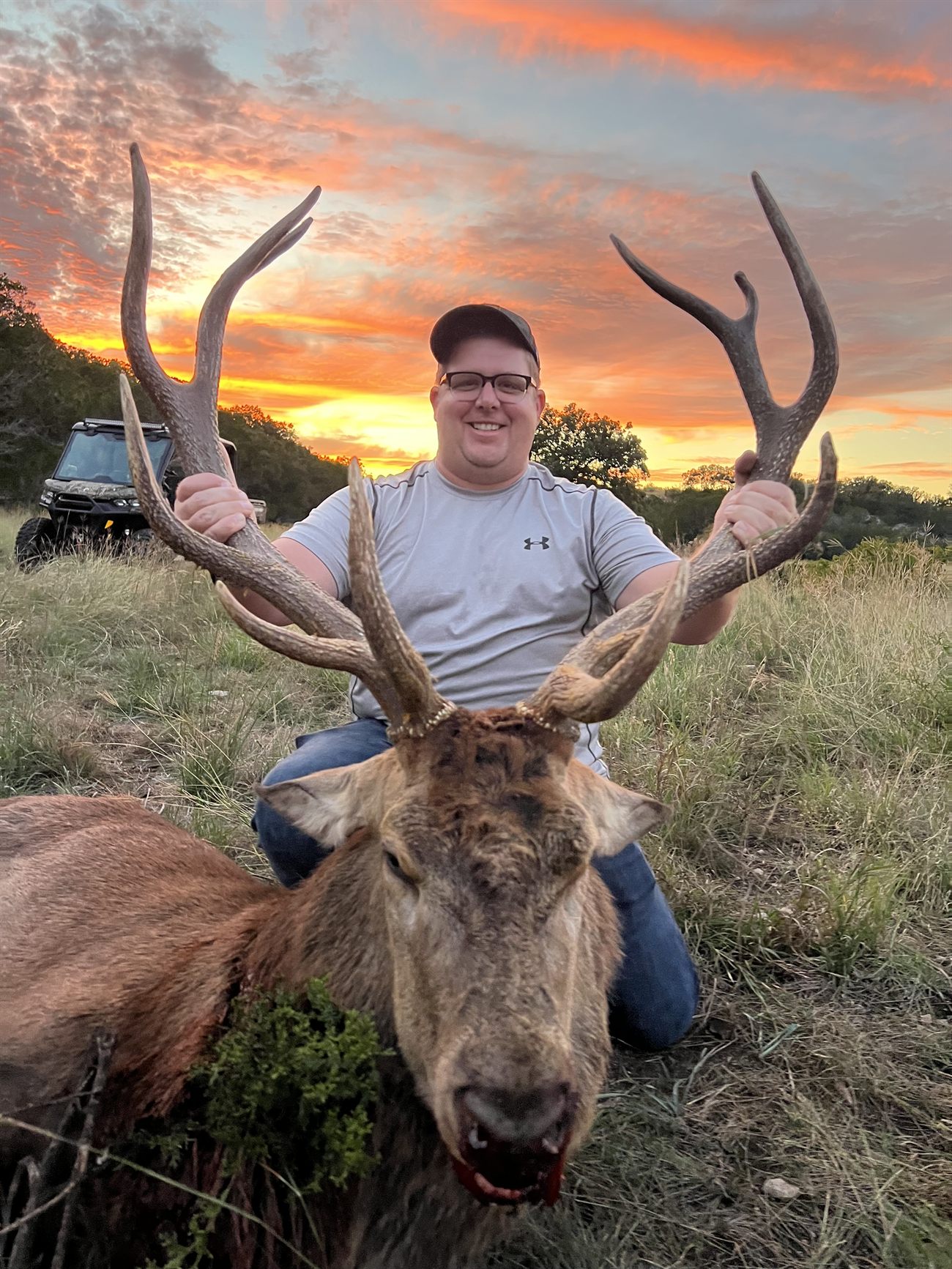 A hunter with a red stag at sunset