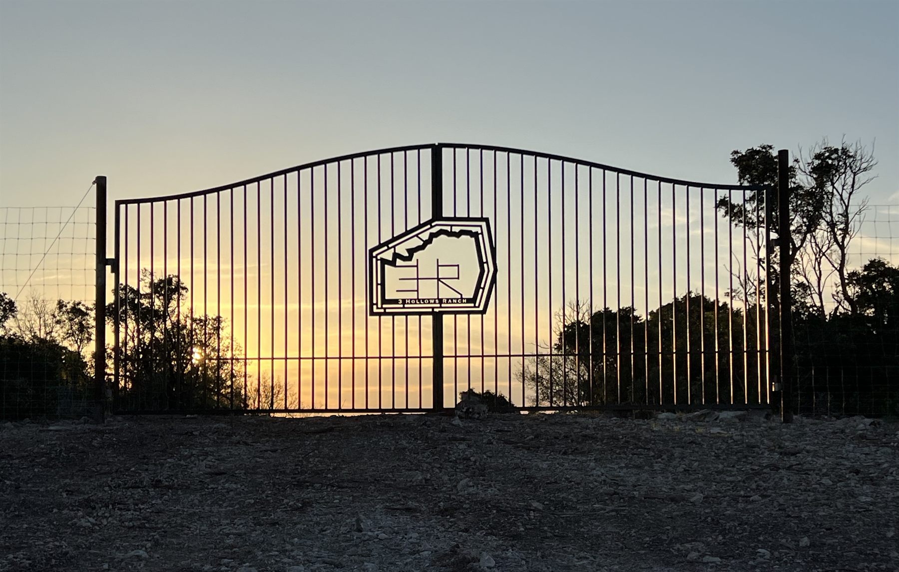 The 3 Hollows Ranch entry gate at sunset